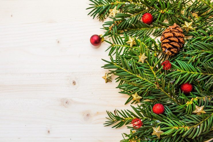 Weihnachtsgesteck mit Tannenzapfen, Sternen und Christbaumkugeln, darunter ein Holztisch zu sehen